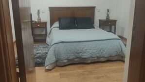 Un dormitorio con cama, suelo de madera y techo con vigas a la vista.