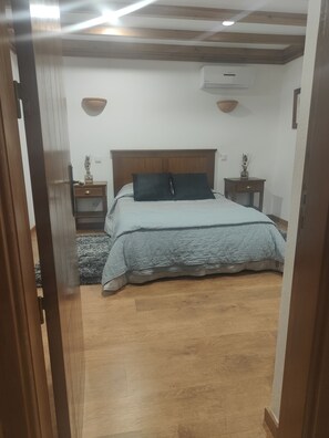 A bedroom with a bed, wooden floor, and a ceiling with exposed beams. - Monte das Medronheiras House (Boliqueime)