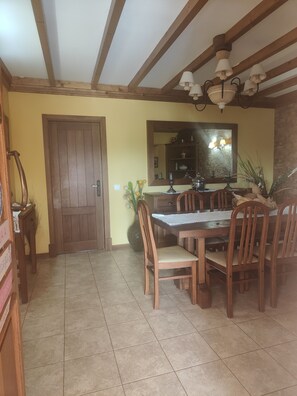 A dining area with a wooden table and chairs, a tiled floor, a wooden door, and a mirror above the table. - Monte das Medronheiras House (Boliqueime)