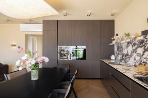 Eine moderne Küche mit Einbauofen, einem Essbereich mit schwarzem Tisch und Stühlen sowie einer Tischvase mit Blumen.