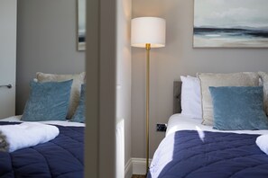 Ein Hotelzimmer mit Bett, Stehlampe und einem Gemälde an der Wand.