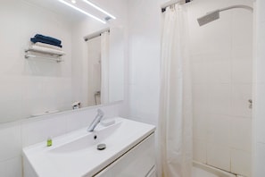 Un bany amb un mànec blanc, un mirall i una dutxa.