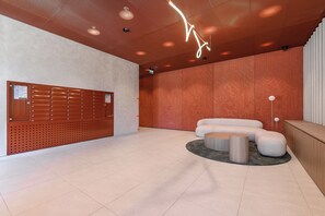 Eine moderne Lobby mit einer Holzwand, einer Sitzecke und einer Decke mit eingelassener Beleuchtung.