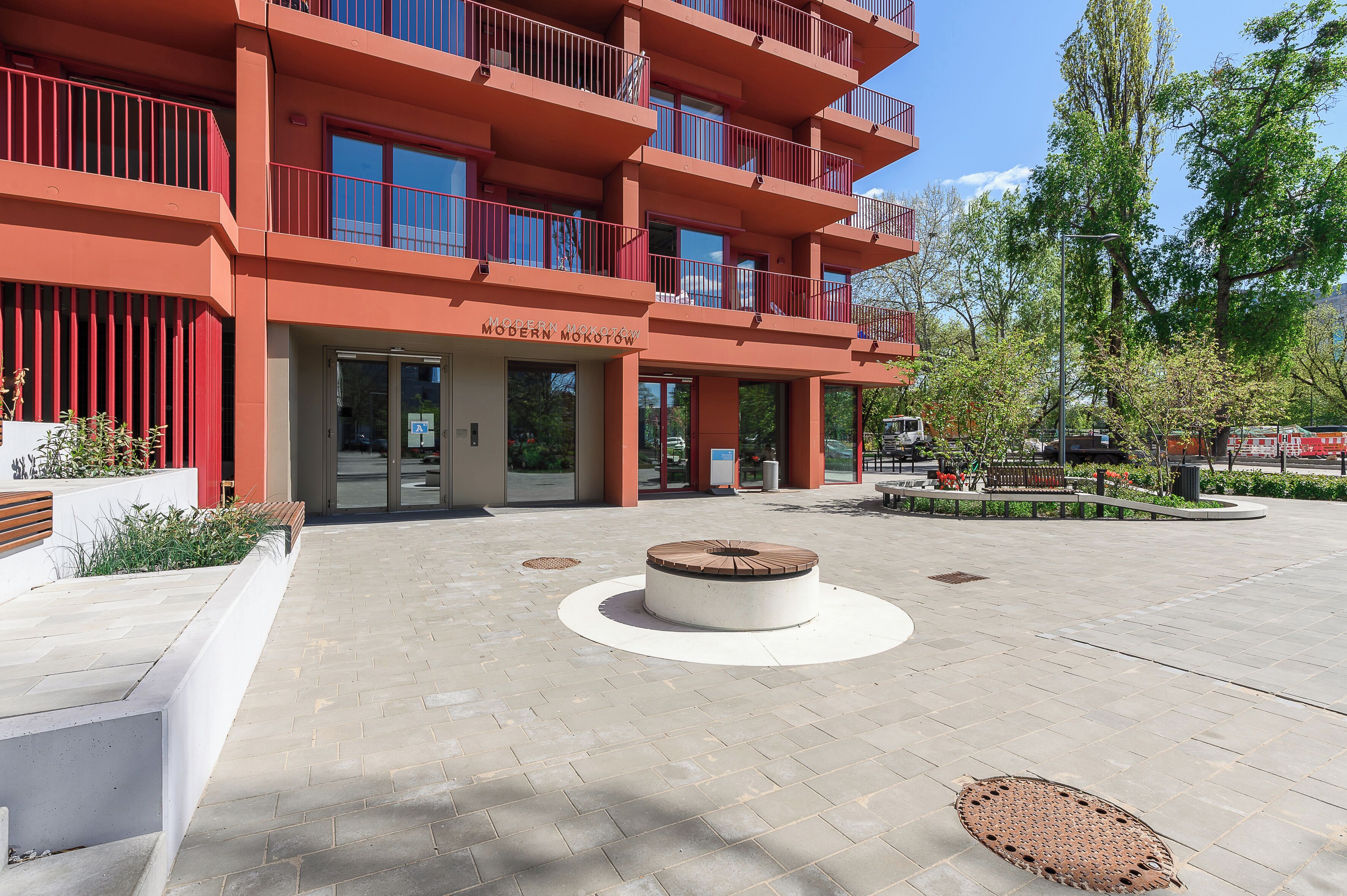 A multi-story building with balconies, a central courtyard with a circular seating area, and a sign reading 'MODERN MOKOTOW.'