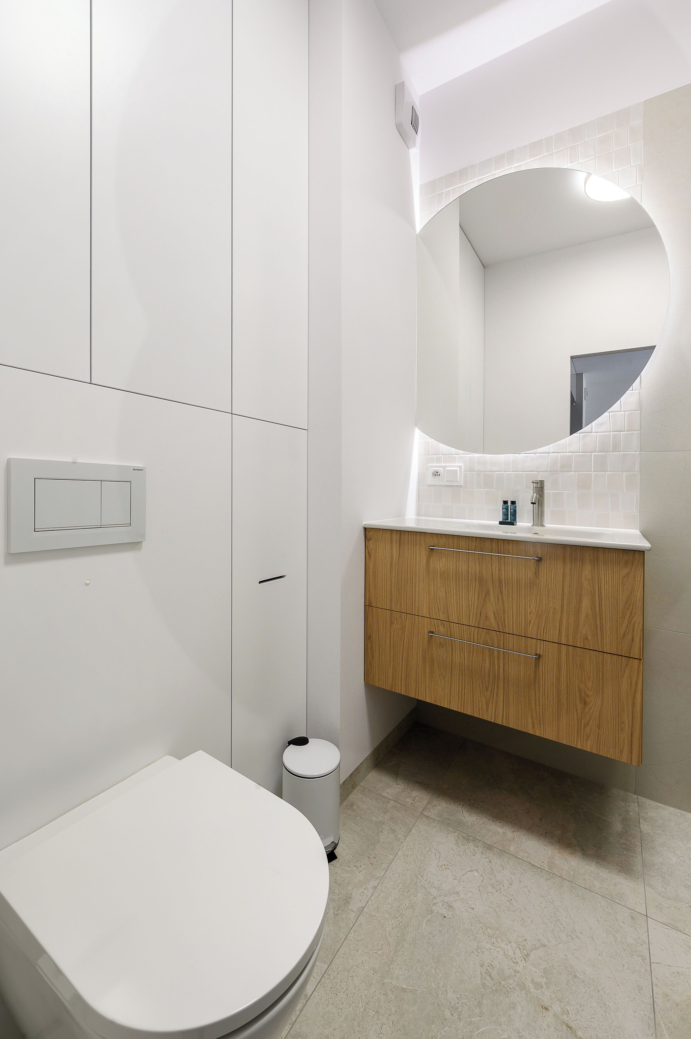 Un bagno moderno con un water, un lavandino con specchio e un cestino.