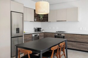 A modern kitchen with a central island, stainless steel appliances, and wooden cabinetry. - 2 Bedroom Elegant Bo-Kaap Escape (Cape Town)