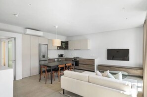 A modern kitchen with a dining area, a sofa, and a TV. - 2 Bedroom Elegant Bo-Kaap Escape (Cape Town)