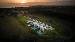 A modern villa with a pool, surrounded by greenery and a sunset view. - Sevene Villas (Kourouta)