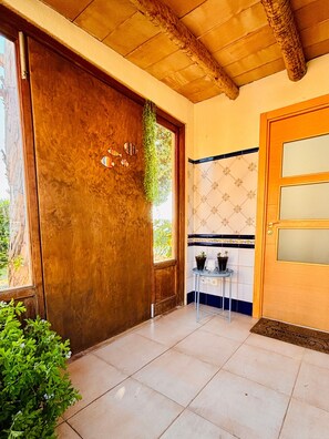 Eine Holztür mit Fenster, ein kleiner Tisch mit Topfpflanzen und ein Fliesenboden.