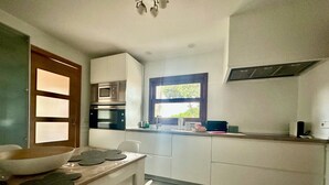 A modern kitchen with white cabinets, a built-in oven, and a window with a view. - Independent House for Two with Pool and Garden (El Turó)