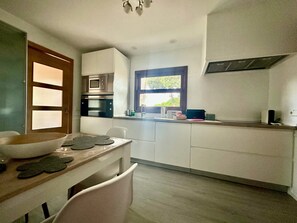Eine moderne Küche mit weißen Schränken, einem eingebauten Backofen und einem Fenster mit Blick.