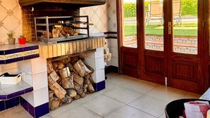 A kitchen with a wood-fired oven, tiled walls, and a view through a glass door. - Independent House for Two with Pool and Garden (El Turó)