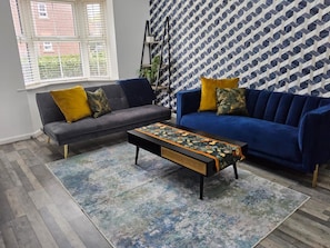 A living room with two sofas, a coffee table, and a patterned rug. - Comfortable 3BR Family Home | Free Parking Included (Chester)