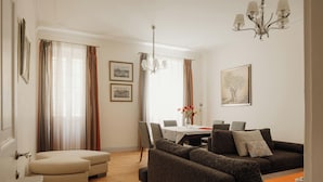 Ein Wohnzimmer mit Sofa, Hocker, Esstisch, Stühlen und einer Chandelier.