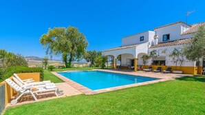 A pool with lounge chairs, a white building with arches, and a clear blue sky. - Private Villa Cortijo Sierra y Lago (Arcos de la Frontera)