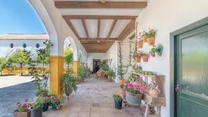 A covered outdoor corridor with potted plants, a wooden bench, and a green door. - Private Villa Cortijo Sierra y Lago (Arcos de la Frontera)