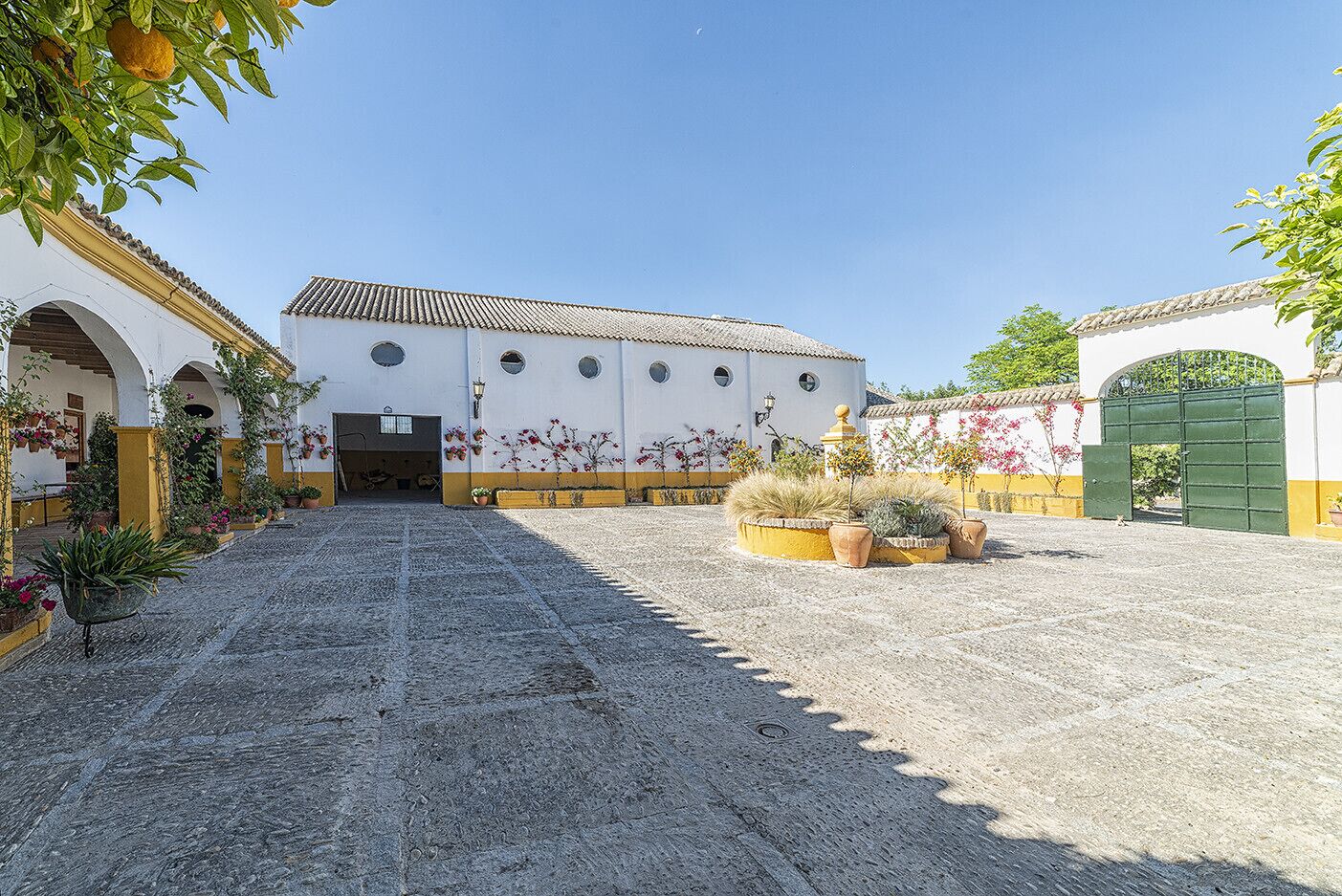 Un patio con un edificio de tejado de azulejos y una puerta verde.