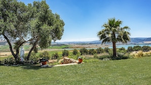 A grassy landscape with a statue, trees, and a view of distant hills and water. - Private Villa Cortijo Sierra y Lago (Arcos de la Frontera)