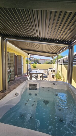 A hot tub under a pergola with a patio table and chairs, surrounded by yellow walls and a view of the neighborhood. - The Yellow Cube - Mediterranean Living (Kožino)