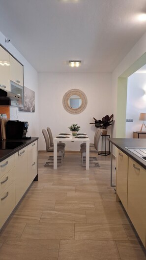 A modern kitchen with a dining area, a coffee machine, and a mirror on the wall. - The Yellow Cube - Mediterranean Living (Kožino)