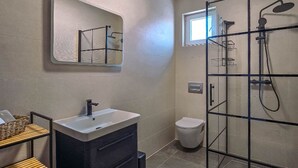 Moderni kylpyhuone, jossa on lasinen suihkuseinä, allaskaappi ja wc.