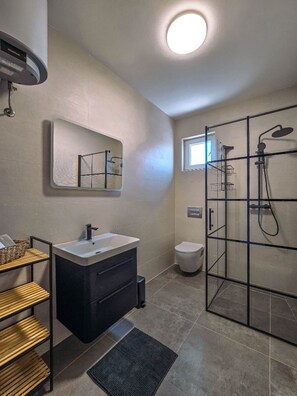 Ein modernes Badezimmer mit Duschkabine aus Glas, einem Waschtisch und einer Toilette.