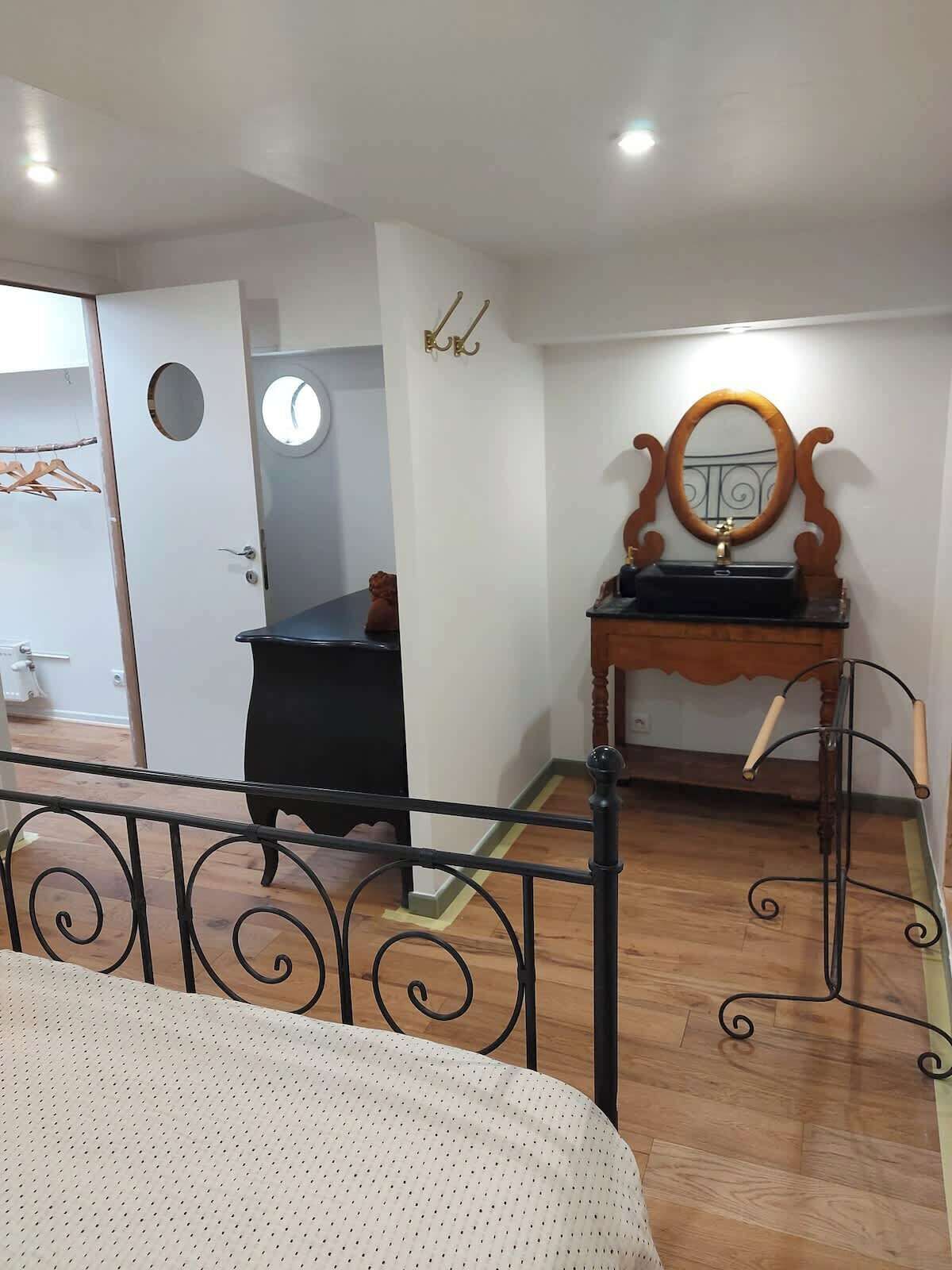 Un dormitorio con cama, cómoda, espejo y puerta que da a otra habitación.