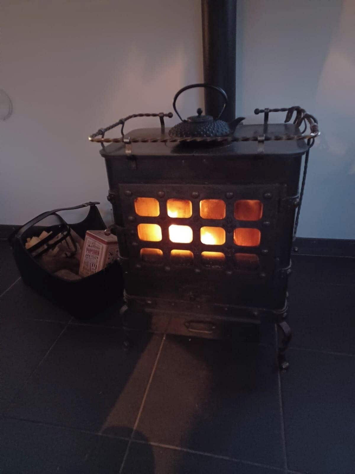 En vedeldad kamin med en korg full med ved bredvid.