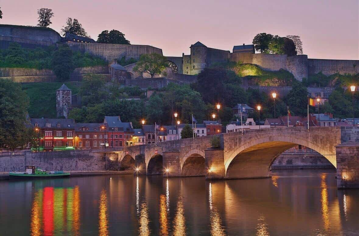 Un ponte di pietra che sovrasta un fiume, con uno skyline urbano sullo sfondo.