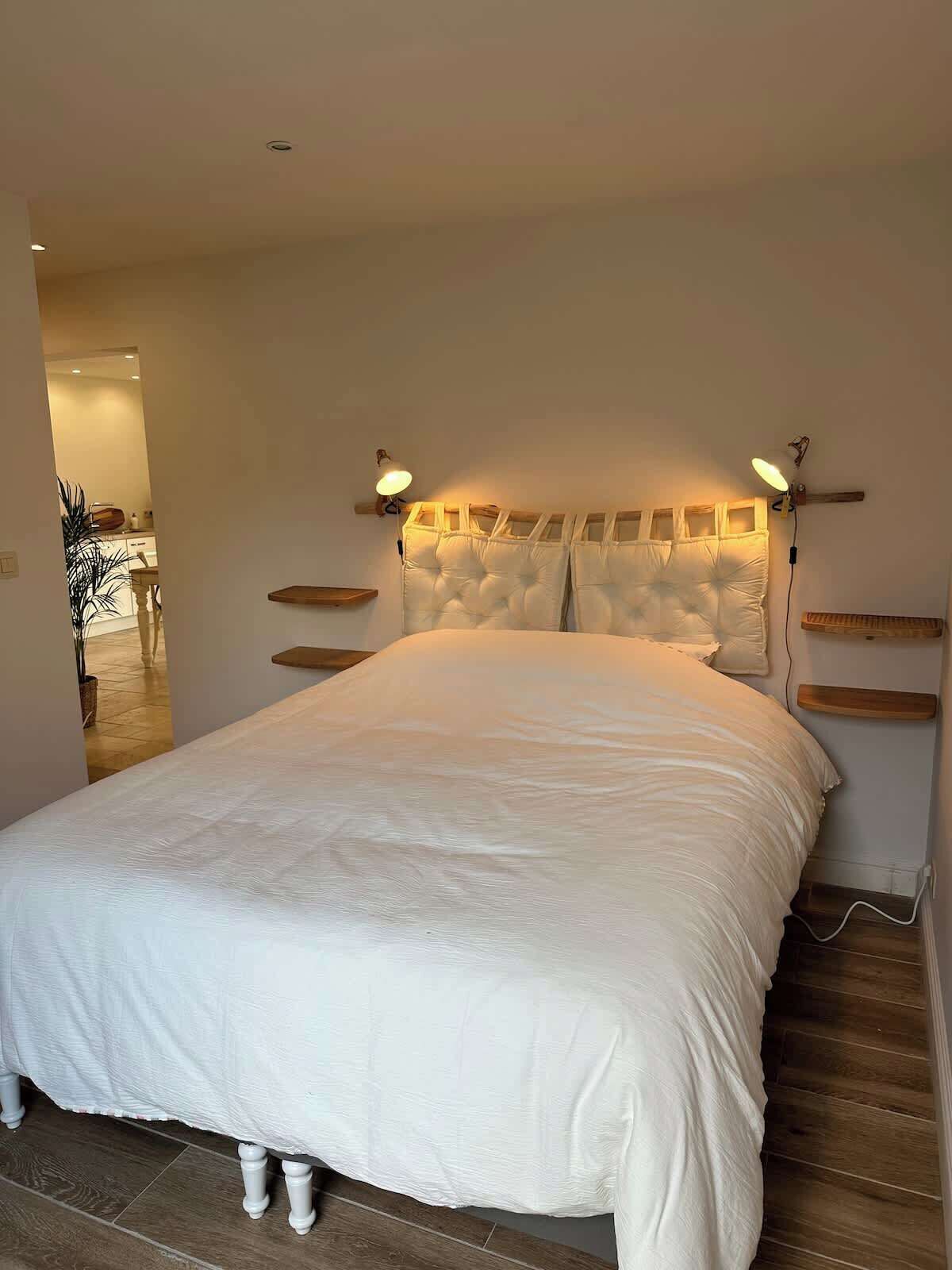 A bedroom with a large bed, two bedside lamps, and a wooden headboard.