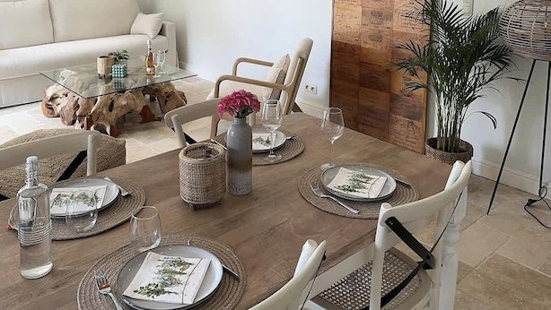 Een eetgedeelte met een houten tafel voor vier personen, omringd door witte stoelen.