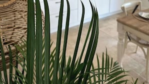 Een moderne keuken met witte kasten, een houten eettafel en een potplant op de voorgrond.