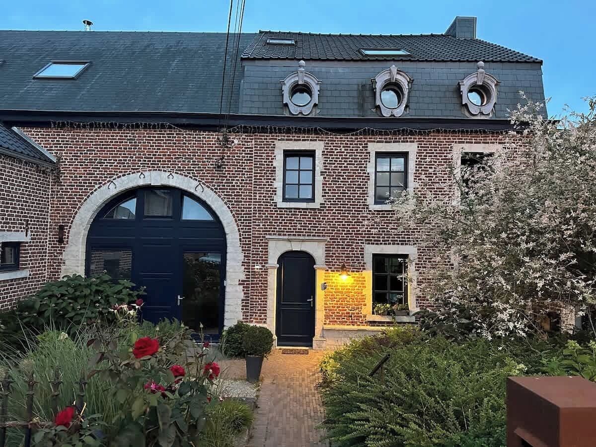 Ein Backsteinhaus mit großem Bogenportal, einer kleineren Tür und einem Fenster mit einer Leuchte.