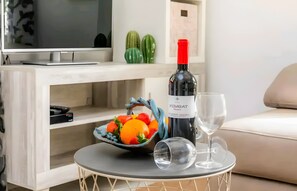 A modern living room with a TV, a wine bottle, a glass, and a fruit bowl on a small round table. - Casa Cactus, Can Picafort, Mallorca (Can Picafort)