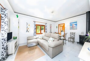 A modern living room with a sectional sofa, a TV, and a dining area with chairs. - Casa Cactus, Can Picafort, Mallorca (Can Picafort)