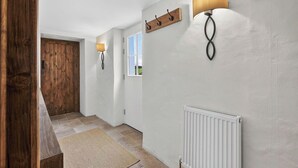 A hallway with a wooden door, a white radiator, and wall-mounted lighting fixtures.