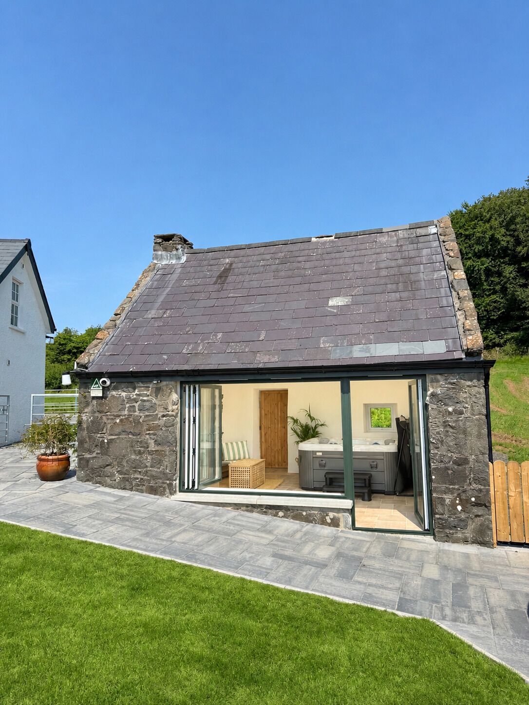 Una casa moderna con fachada de piedra, techo de tejas y puerta de cristal que da a un espacio con cocina y zona de estar.