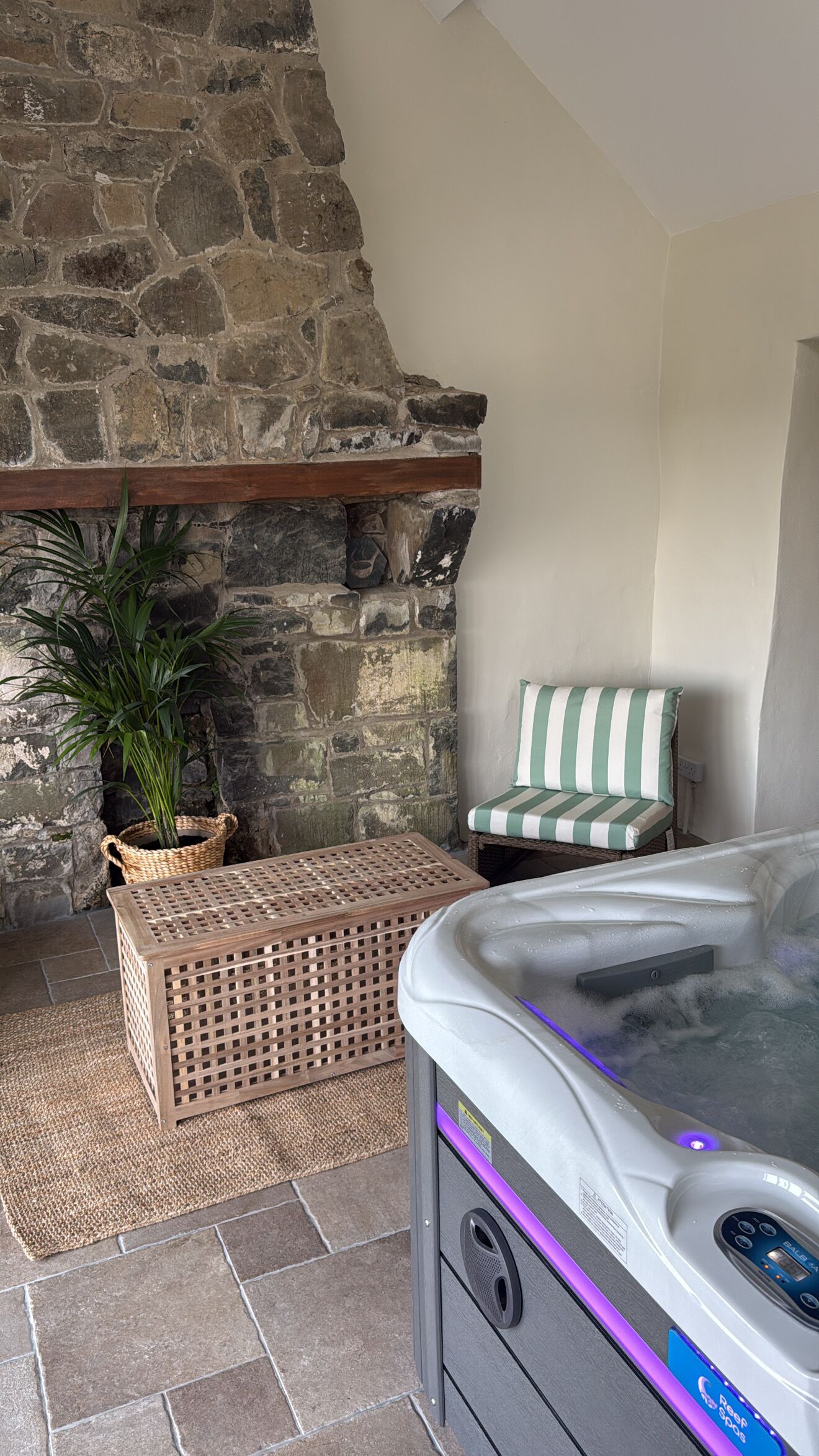 Una chimenea de piedra, una cesta de mimbre, una silla a rayas y un jacuzzi.