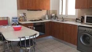 Une cuisine compacte avec des meubles en bois, un évier en acier inoxydable, un four à micro-ondes et un lave-linge.