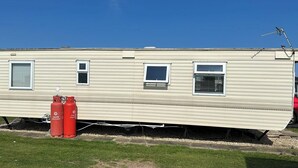 A mobile home with three windows, a chimney, and two red propane tanks. - Caravan Situated on Coastfields, Ingoldmells (Skegness)