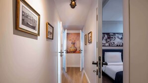 Un pasillo con cuadros enmarcados, un florero y una cama en la habitación.