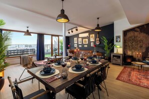 A dining area with a long table set for a meal, a sofa, and a fireplace. - Bosphorus View Apt With 2 Terraces At Monnas Suite (Istanbul)