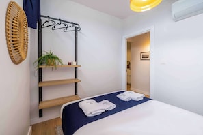 A hotel room with a bed, a wall-mounted shelf with a plant, a hanging rack, and a door leading to another room. - Bosphorus View Apt With 2 Terraces At Monnas Suite (Istanbul)