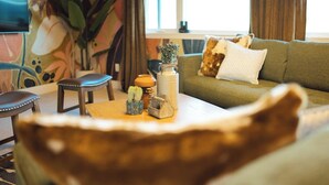 Un salon comprenant un canapé, une table basse agrémentée d’objets décoratifs, un fauteuil et une grande plante.