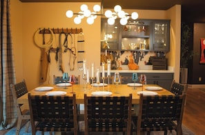 A dining area with a wooden table set for six, surrounded by chairs. - Yellowstone River | Theater+Saloon | Sauna | Views (Livingston)
