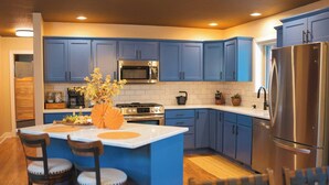 Une cuisine moderne avec des meubles bleus, un réfrigérateur en acier inoxydable et un îlot central doté de tabourets de bar.