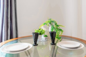 A round glass table with two white plates and two black glasses, accompanied by a small potted plant and a decorative item. - Central - Stay 4 - Paid Parking - Near Transport (Maidstone)