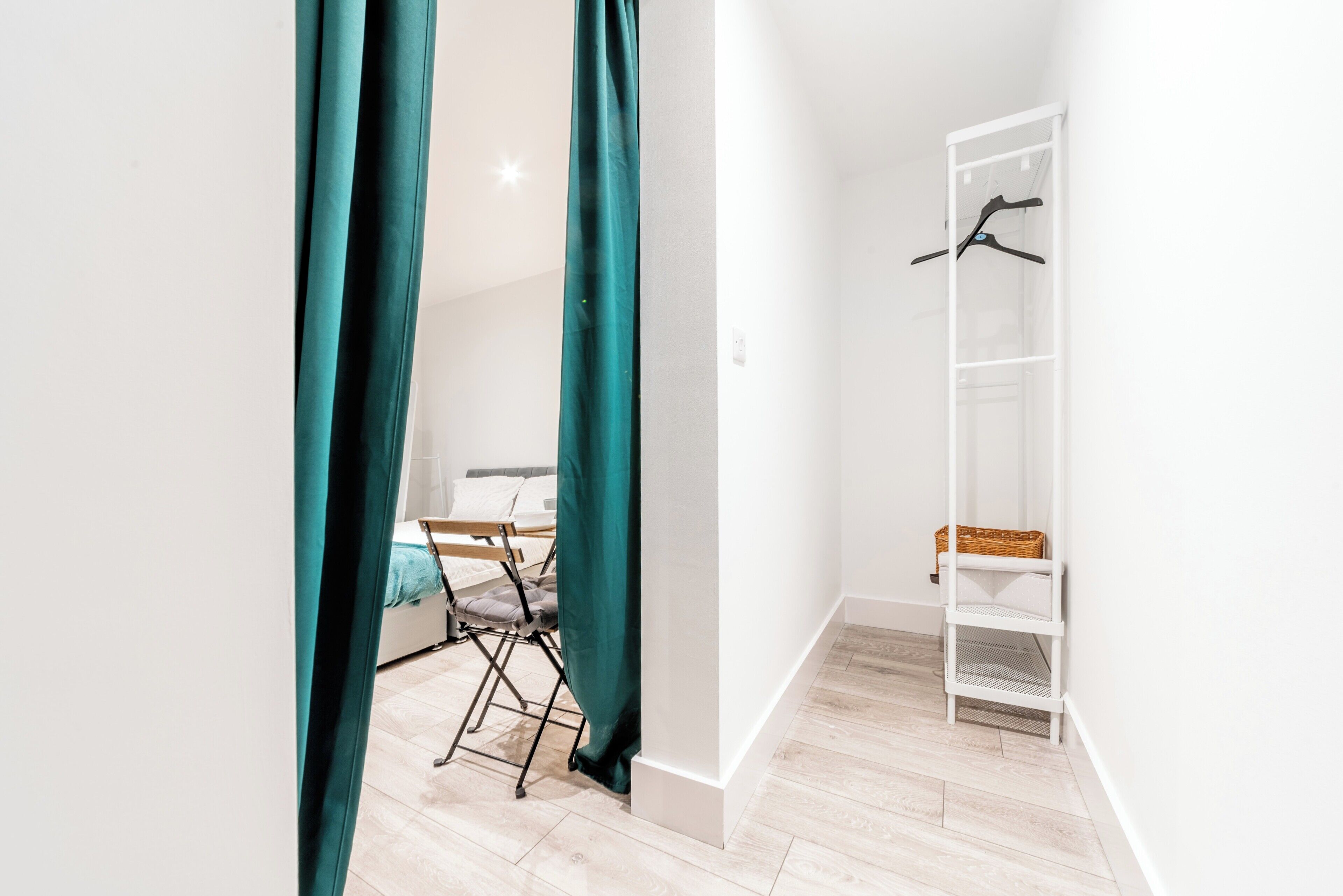 Une chambre avec un lit, un bureau, des rideaux de couleur turquoise, une armoire blanche et une étagère blanche.