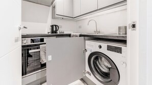Eine kleine Küche mit Einbauofen, Waschmaschine und Kaffeemaschine.