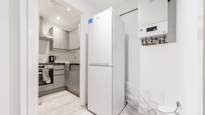 Eine moderne Küche mit einem weißen Kühlschrank, einem Wasserkocher und einem Einbauofen.